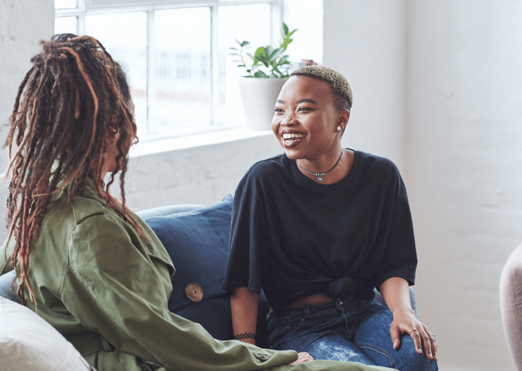 Two Black women having a conversation on a couch.