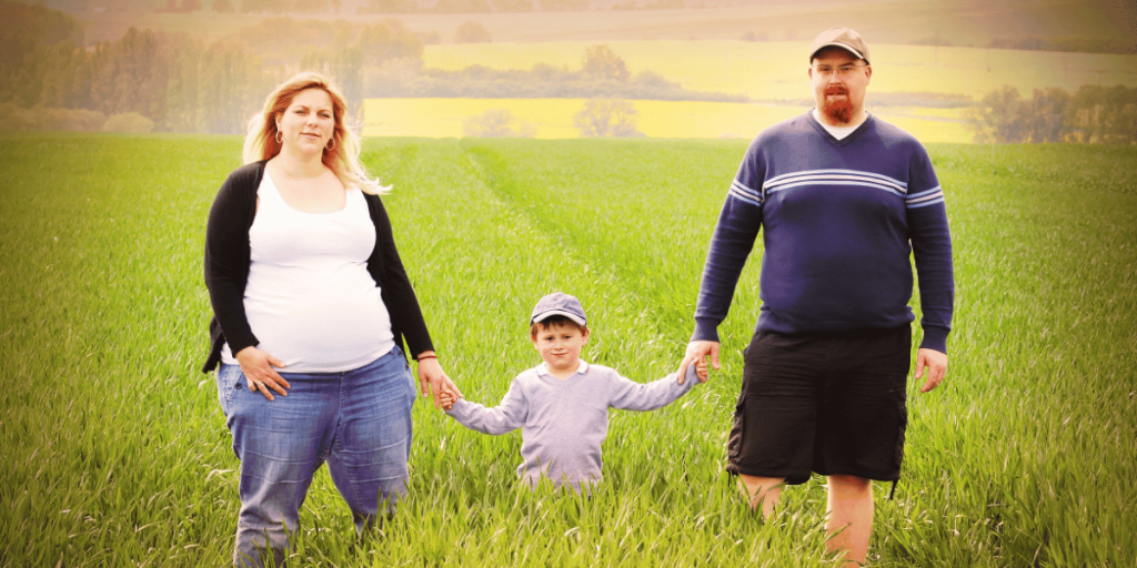 Young farmer's family together on green wheat field. Pregnant mother with father and their little son. 