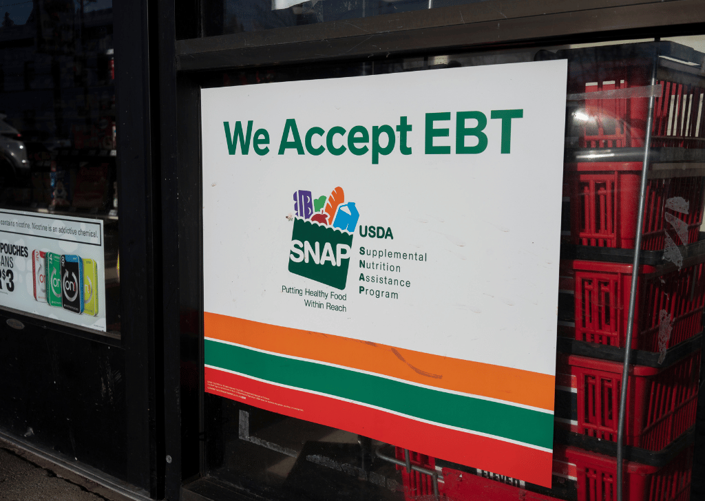 We Accept EBT" sign is seen at the entrance to a 7-Eleven store