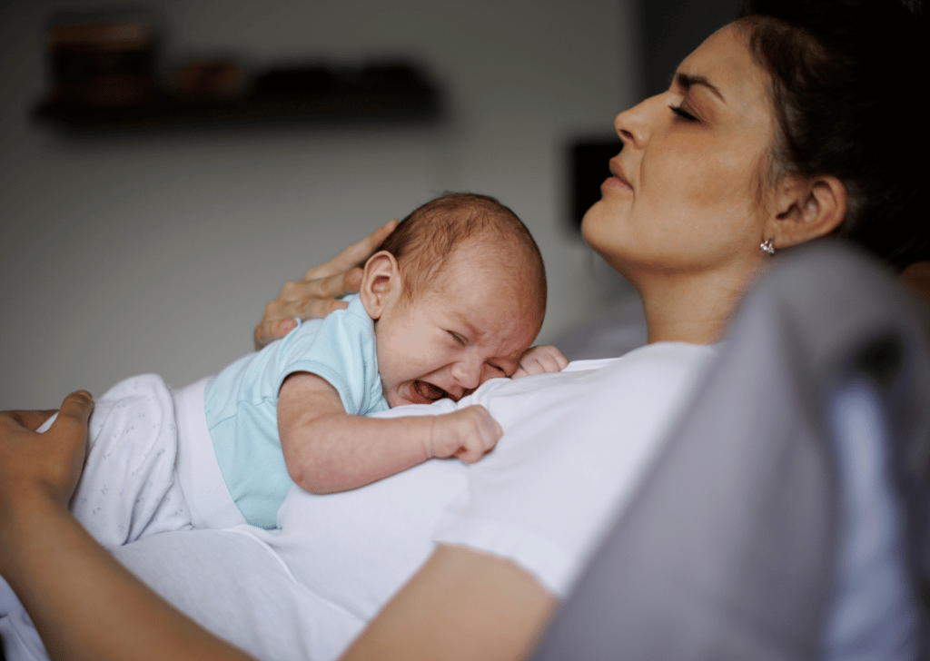 Exhausted new mother holding her crying newborn. 